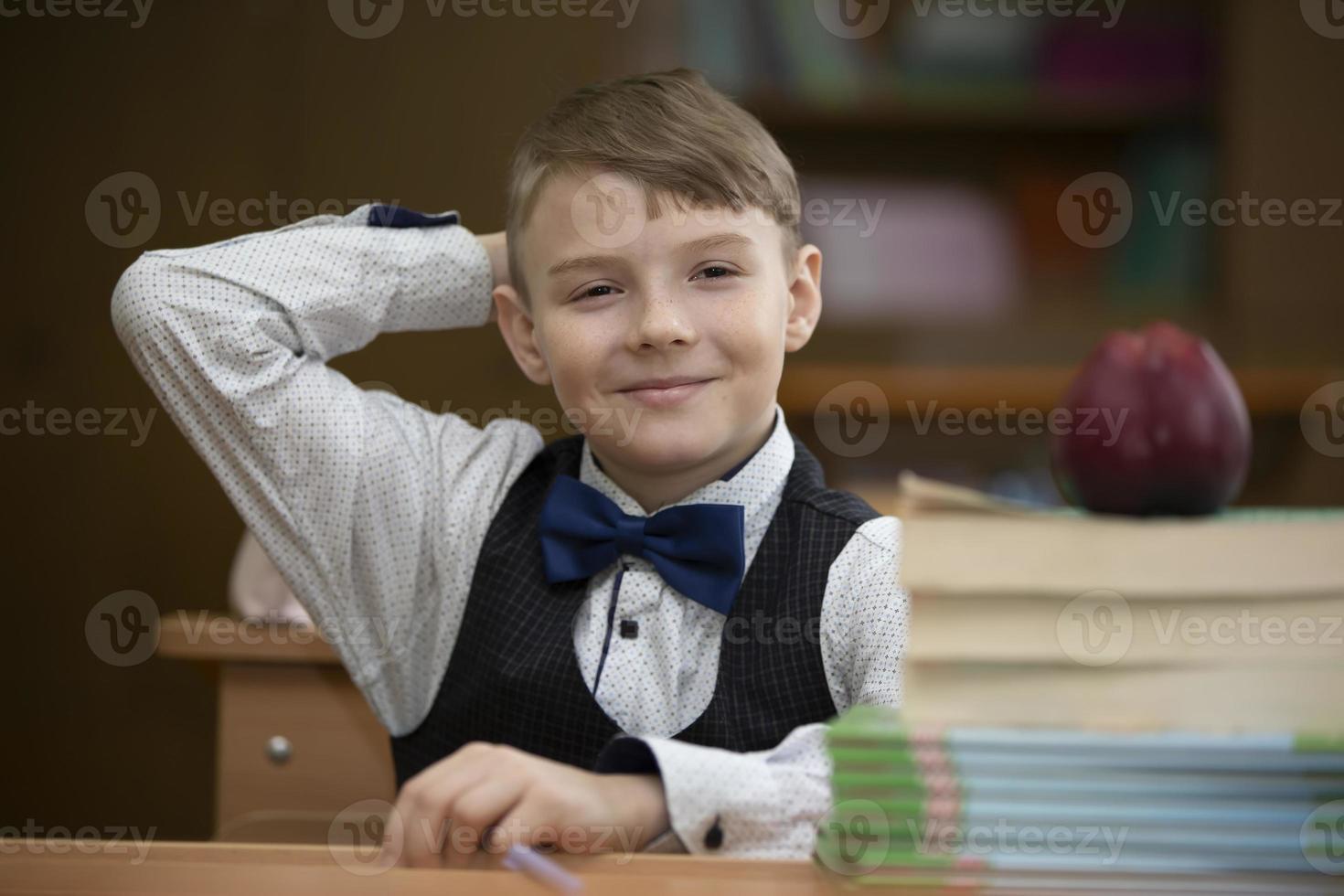 Schoolboy at the desk. Boy in the classroom with books and an apple. Secondary school. Back to school. photo