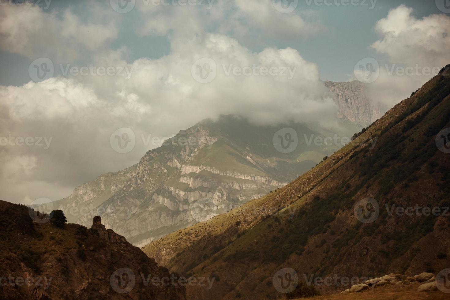 High black rock in low clouds. Surreal gloomy mountains. photo