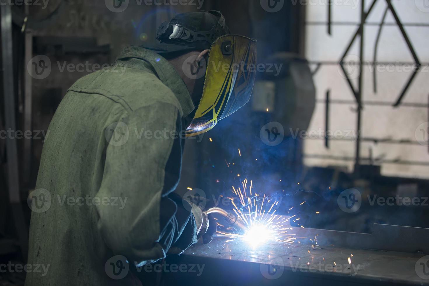 un soldador trabajos con metal en un fábrica tienda. foto