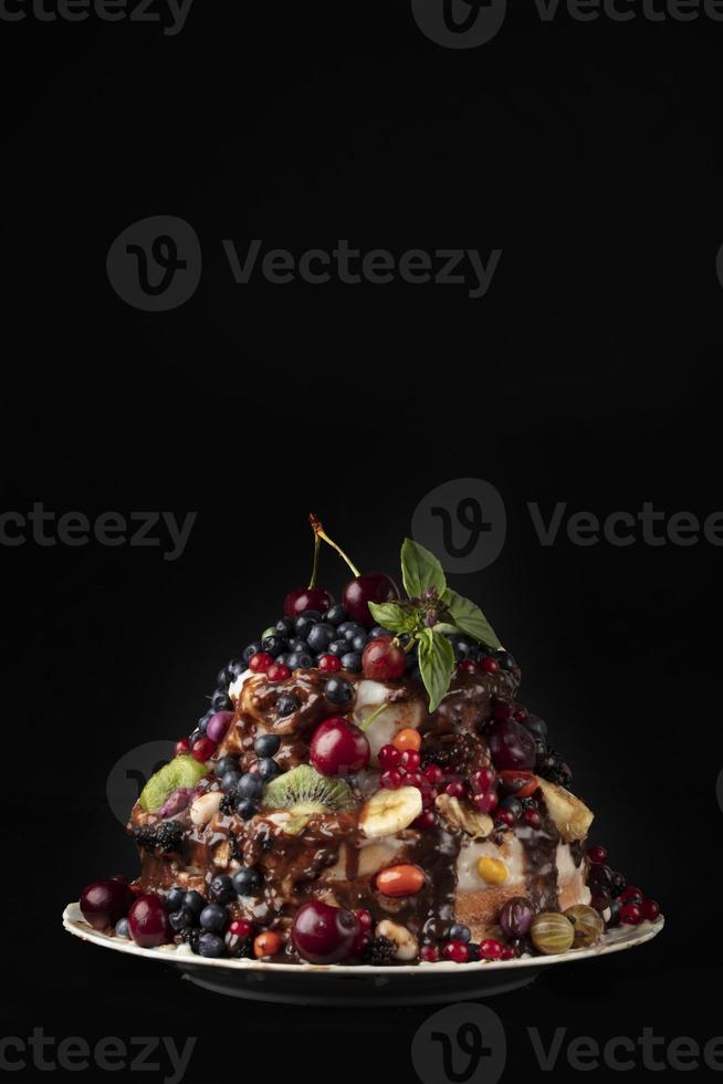 Vertical Beautiful cake decorated with various berries and fruits on a dark background. photo