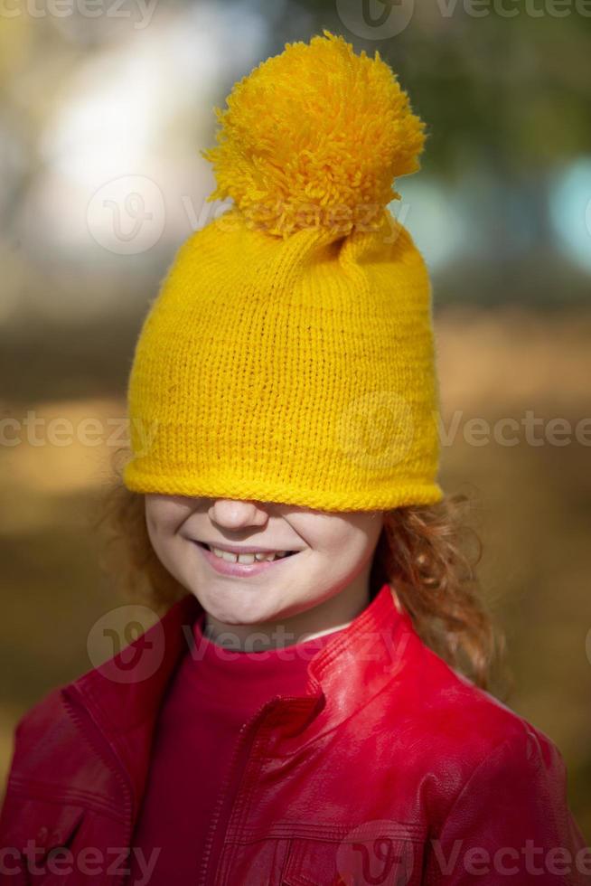 The little girl pulled a yellow knitted hat over her eyes. Fall has come. photo