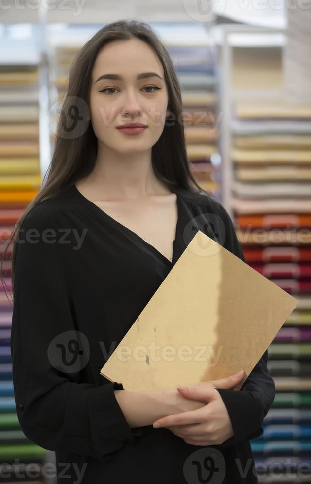 Portrait of a beautiful young girl with a notebook in her hands. Office worker or teacher. photo