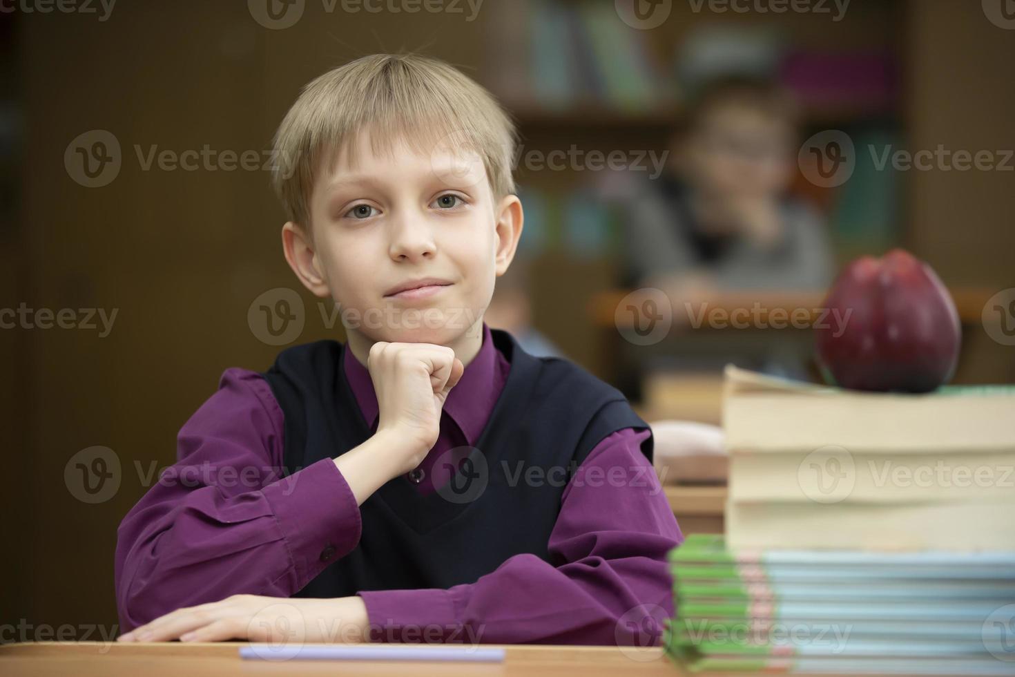 Schoolboy at the desk. Boy in the classroom with books and an apple. Secondary school. Back to school. photo