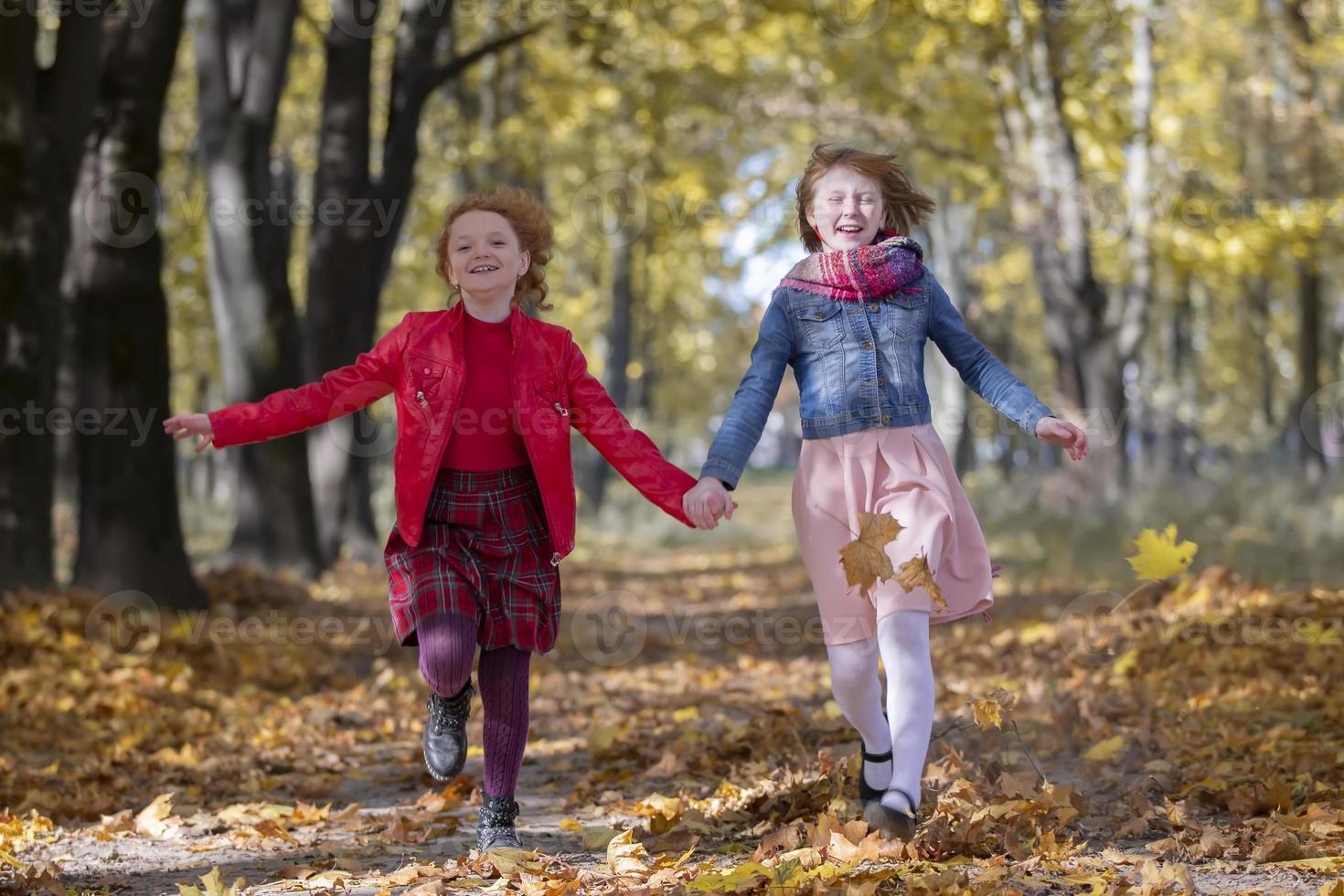 Happy children play in the autumn park on a warm sunny autumn day. photo