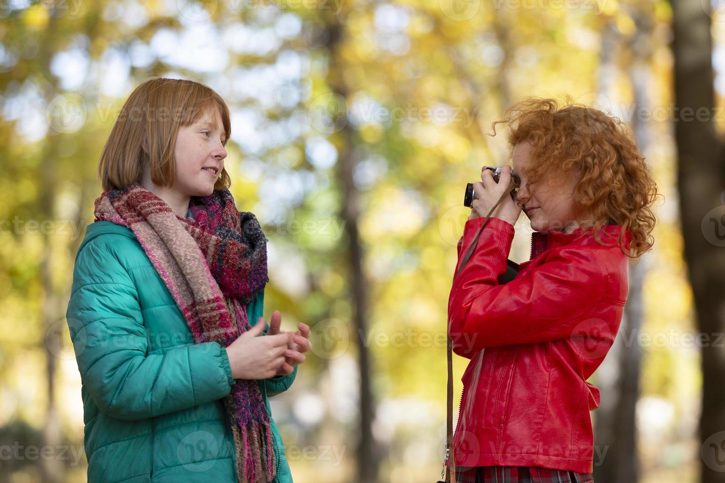 dos Pelirrojo muchachas novias fotografía cada otro en el otoño parque con un retro cámara. foto