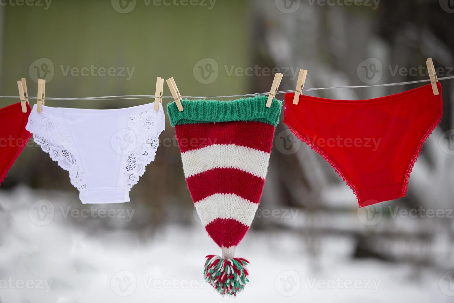 Women's panties and a Christmas hat are dried on a rope. photo