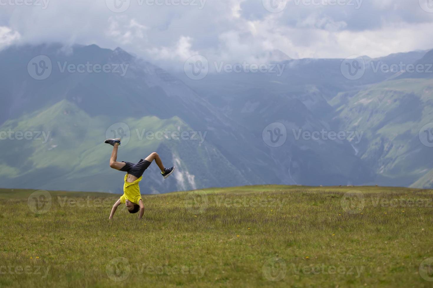 A happy child does somersaults against the backdrop of a mountainous area. photo