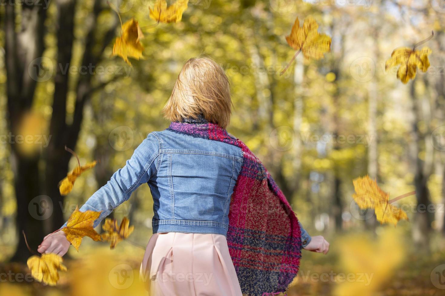 un Pelirrojo niña camina mediante el otoño parque. foto