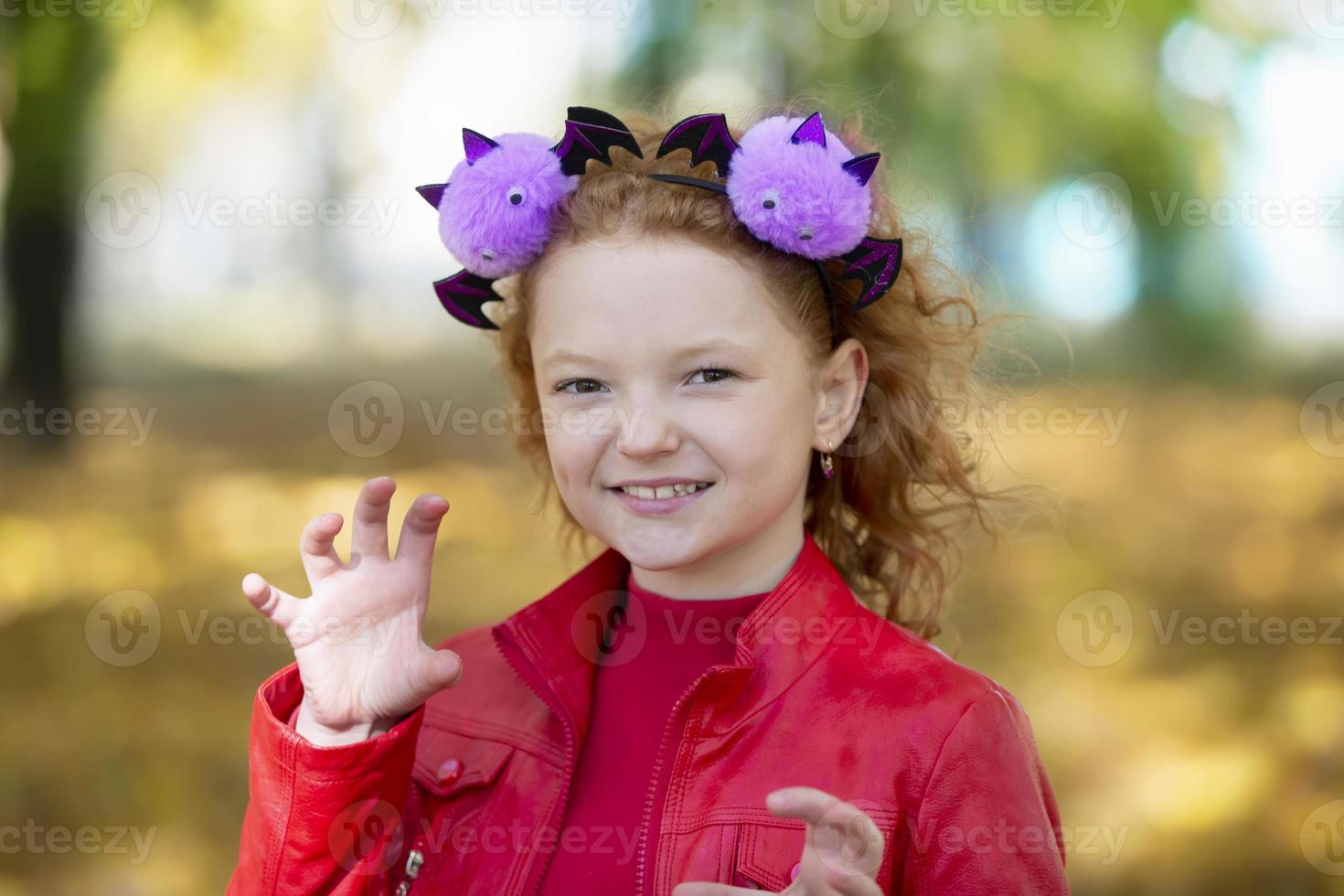 A girl in casual clothes and with a headband with halloween horns scares you. Halloween concept. photo
