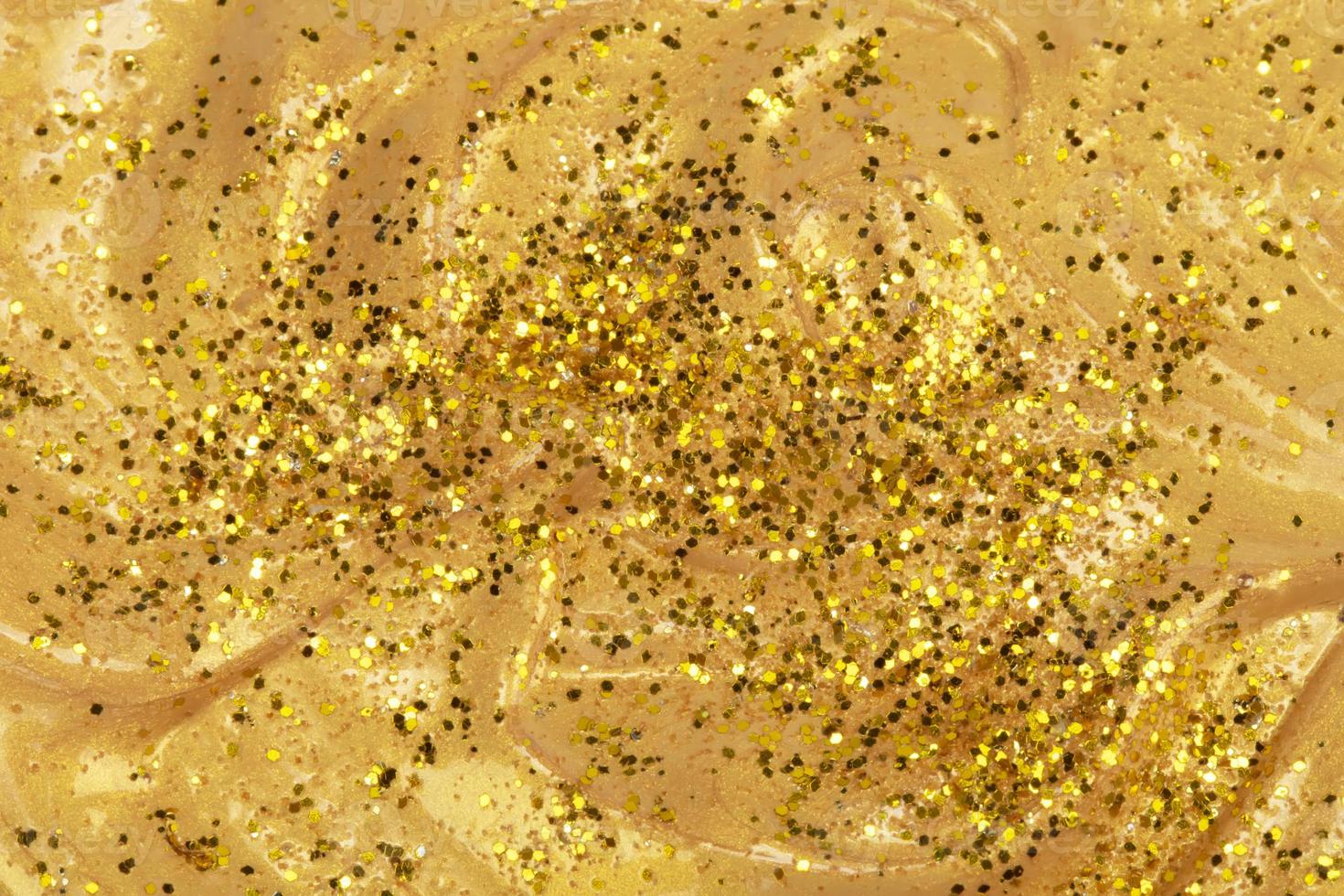 Texture of a flowing gold cosmetic product or acrylic paint covered in glitter photo