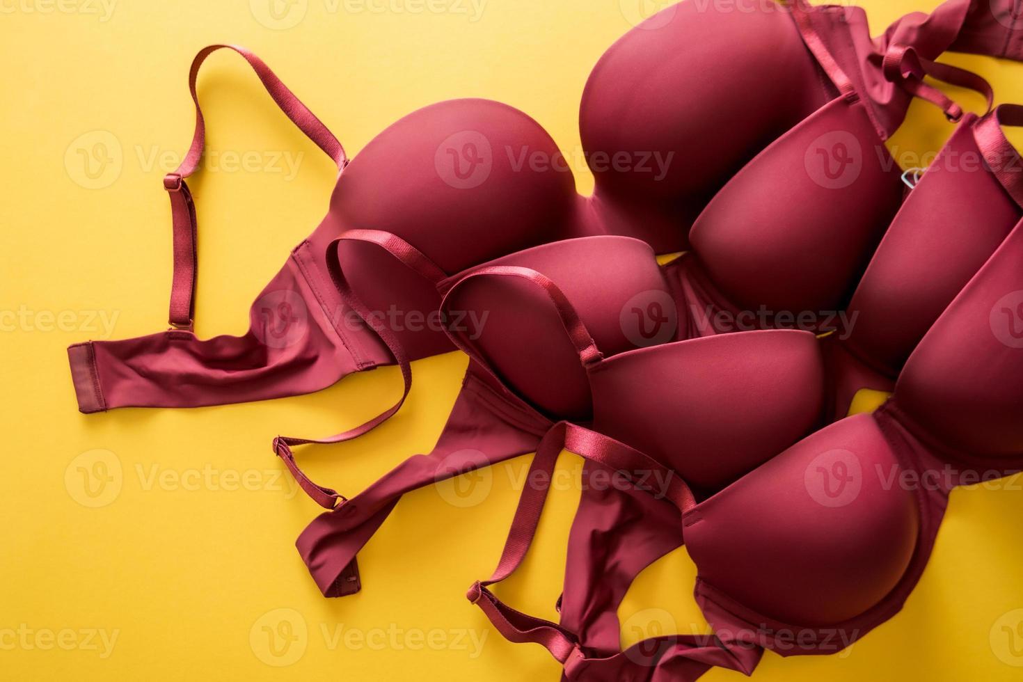 Set of burgundy color bra on yellow background, closeup photo