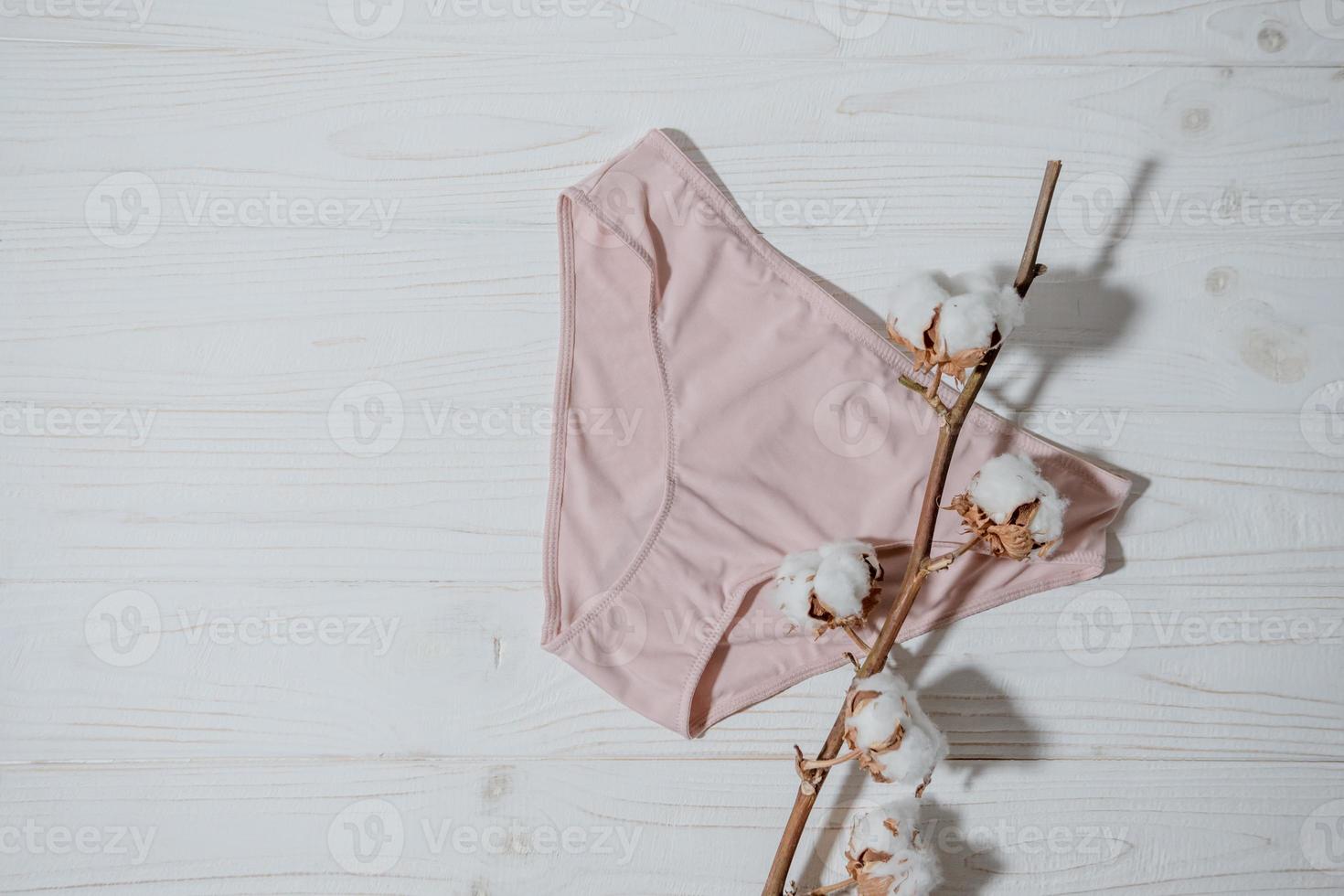 Pink underpants with cotton brunch on wooden background, closeup photo