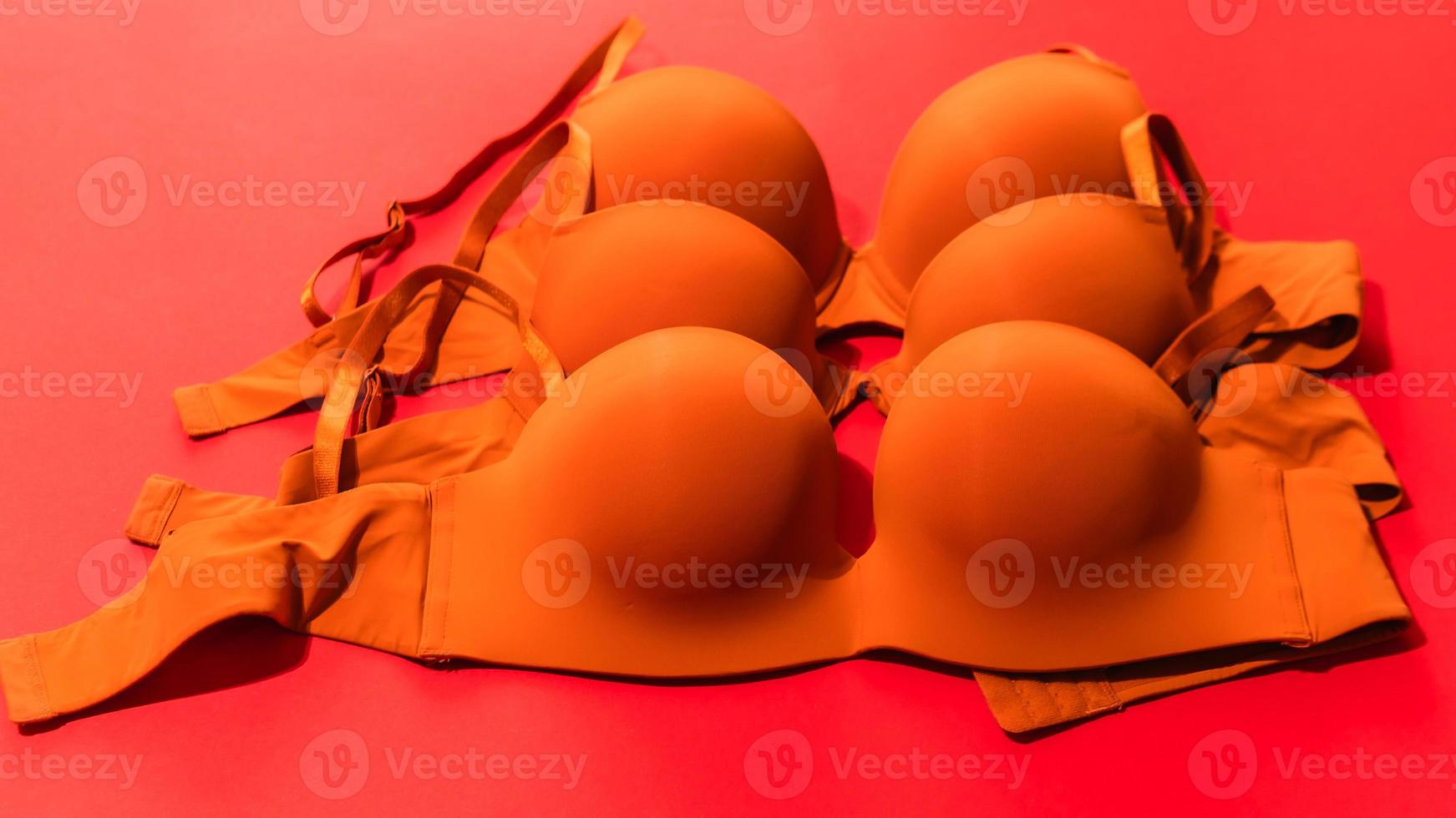 Set of orange color bra on red background, closeup photo