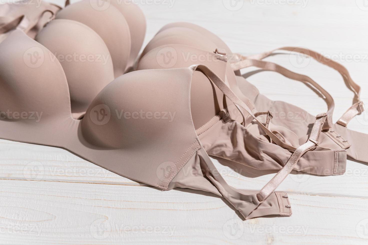 Set of Beige bra on wooden background, closeup. photo