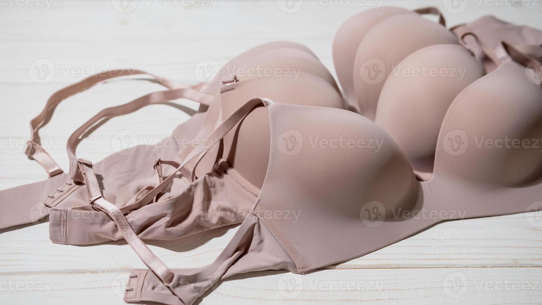 Set of Beige bra on wooden background, closeup. photo