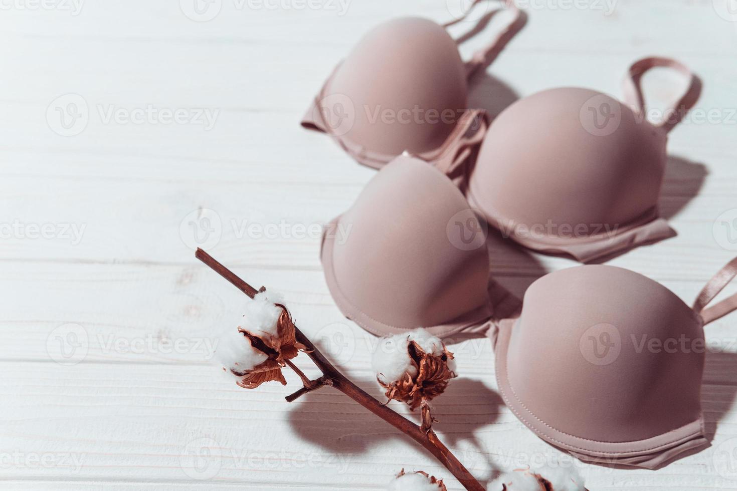 Pink bra with cotton brunch on white wooden background, closeup photo