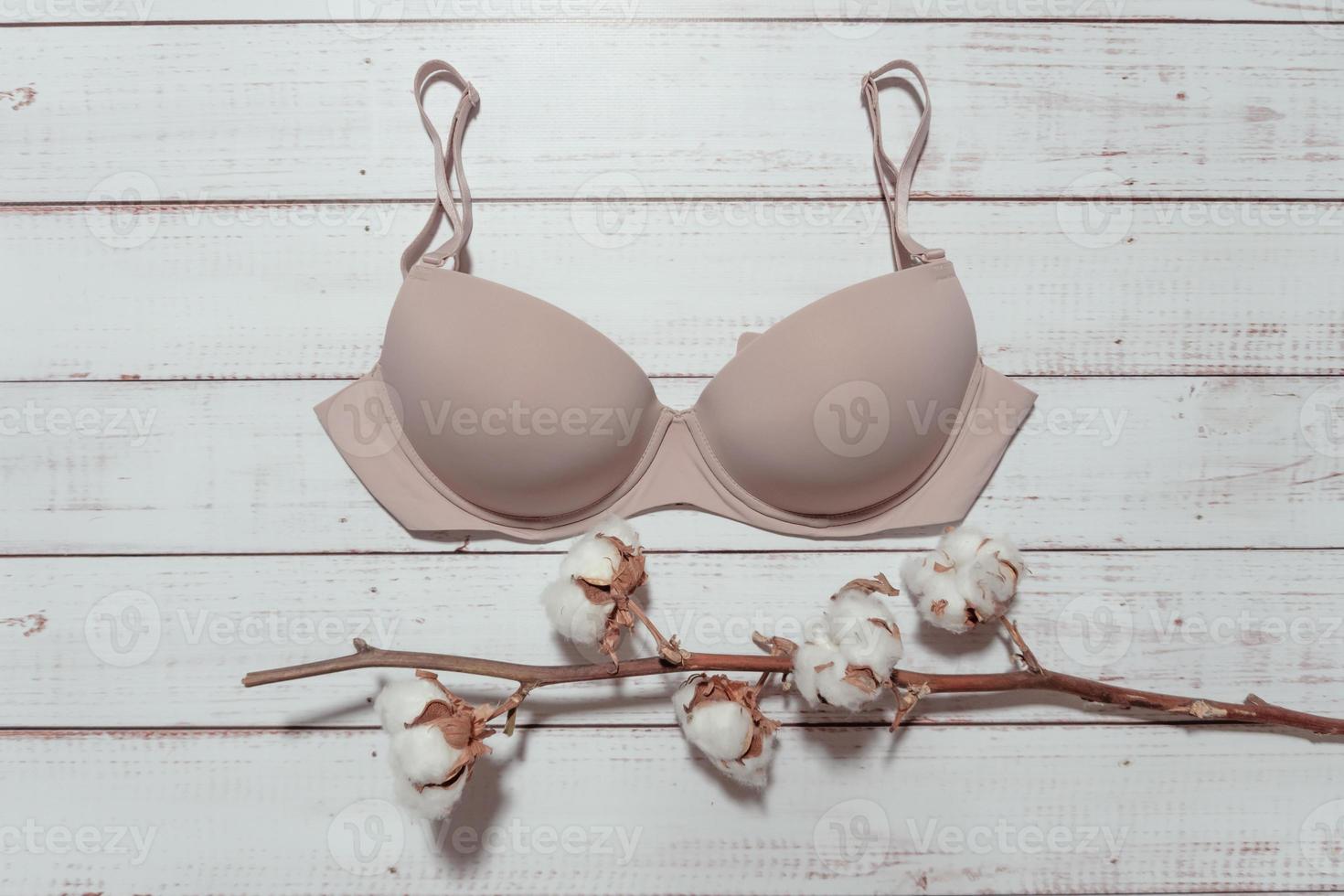 Pink bra with cotton brunch on white wooden background, closeup photo