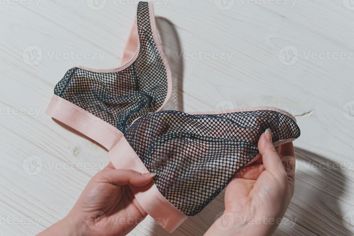 Woman holding lace bra, wooden background, closeup. photo