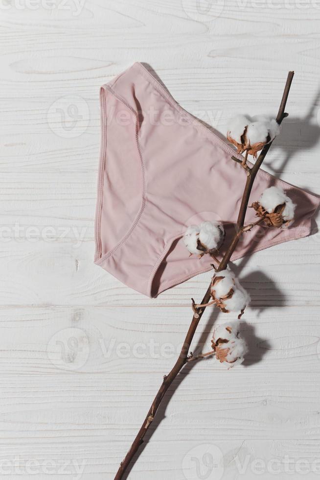 Pink underpants with cotton brunch on wooden background, closeup photo