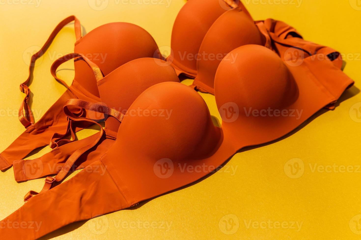 Set of orange color bra on yellow background, closeup. photo