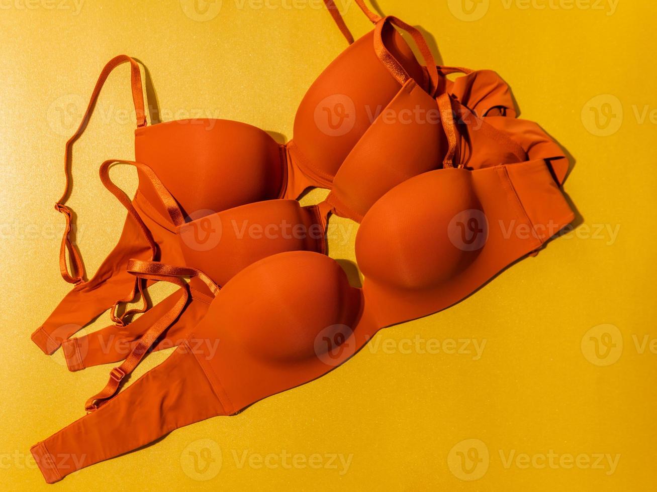 Set of orange color bra on yellow background, closeup. photo