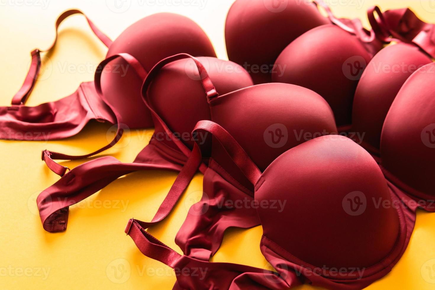 Set of burgundy color bra on yellow background, closeup photo