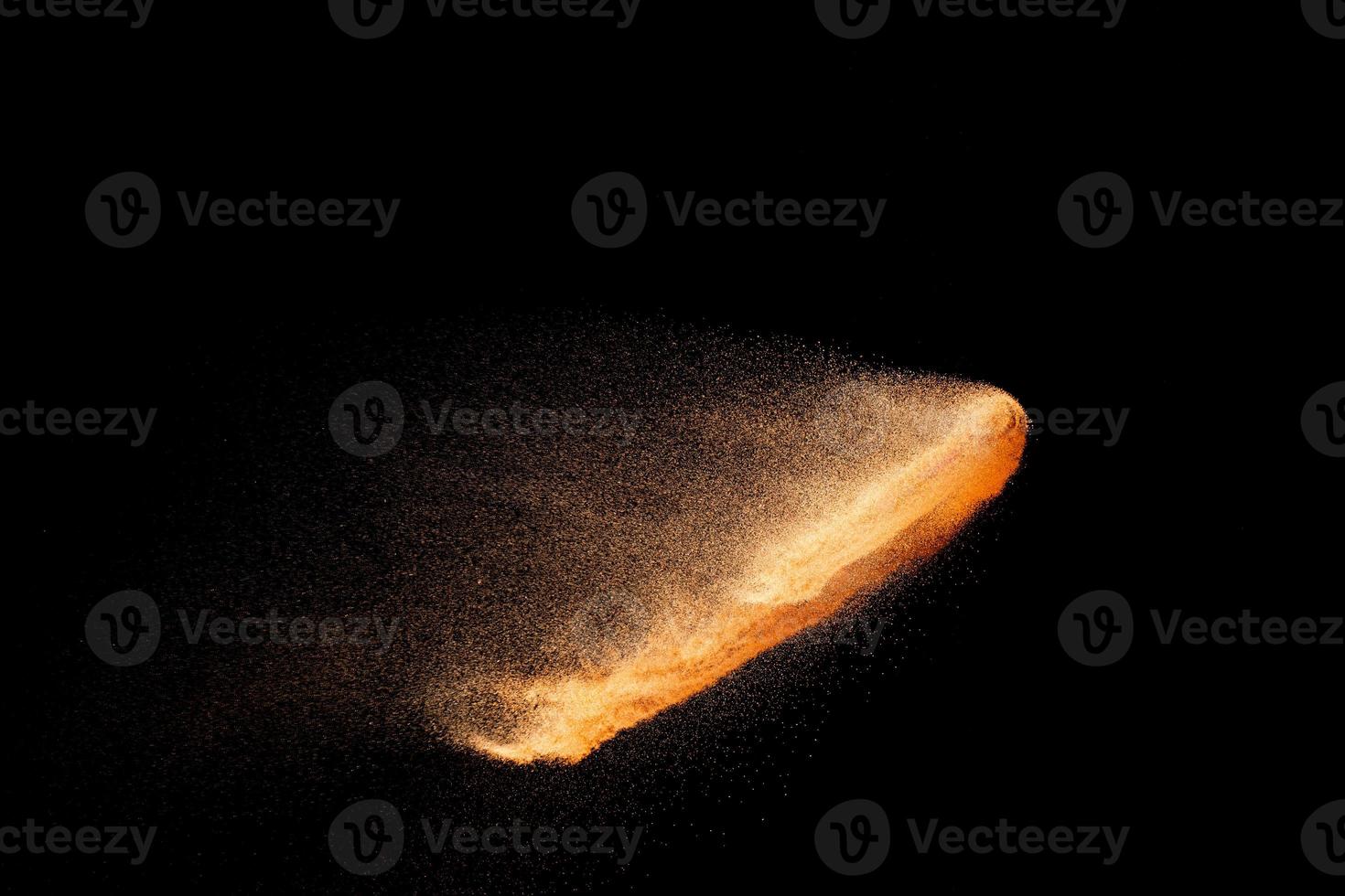 Brown sand explosion isolated on black background. Freeze motion of sandy dust splash. photo