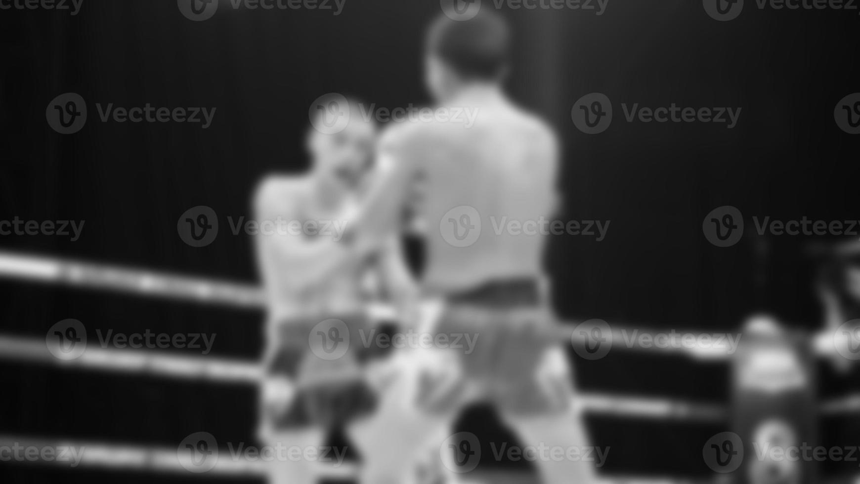 Blurred images black and white photo style of Thai boxing or Muay Thai or Kickboxing which local and foriegn boxer are fighting on the ring at indoor stage as martial art sport. Muay Thai Kick boxing