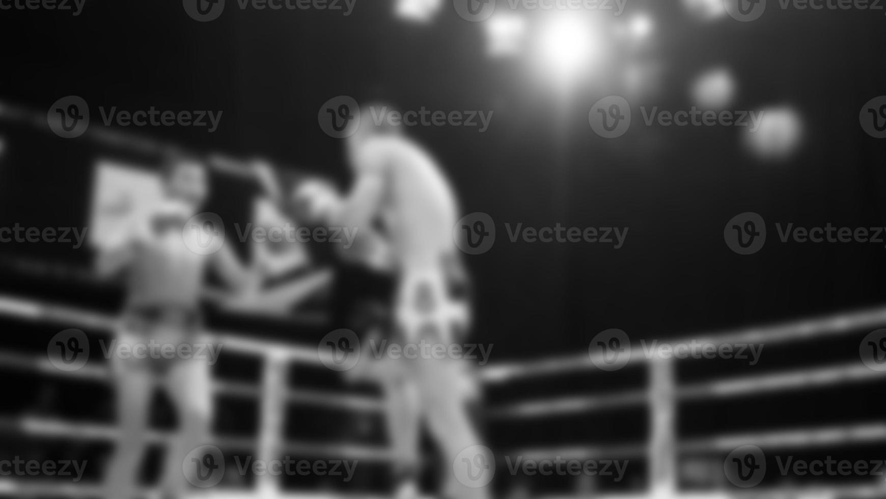 Blurred images black and white photo style of Thai boxing or Muay Thai or Kickboxing which local and foriegn boxer are fighting on the ring at indoor stage as martial art sport. Muay Thai Kick boxing