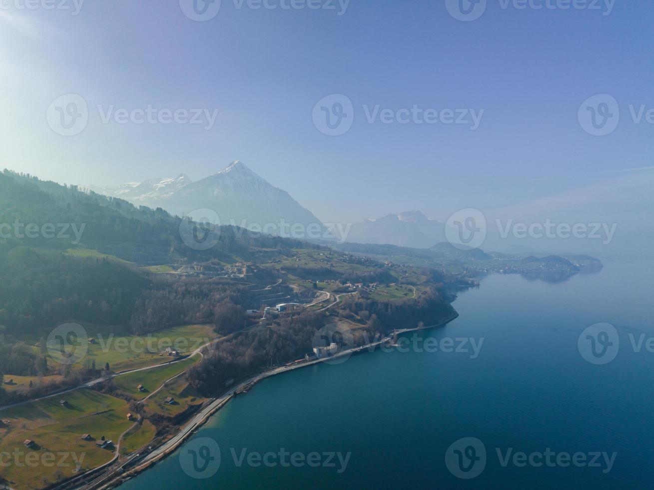 Aerial view of the snow rocky cliffs with forest by the lake. Dramatic and picturesque scene. photo