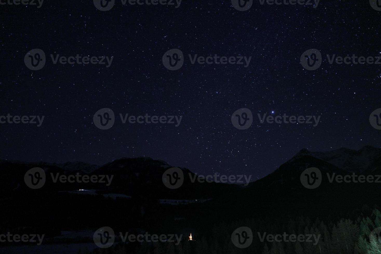 Beautiful sky with stars glowing over silhouette landscape at night photo