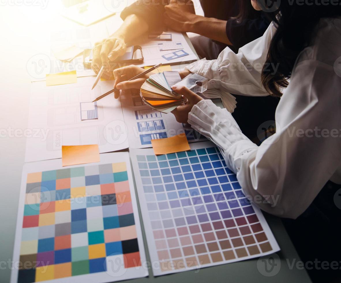 Close up ux developer and ui designer brainstorming about mobile app interface wireframe design on table with customer breif and color code at modern office.Creative digital development agency photo