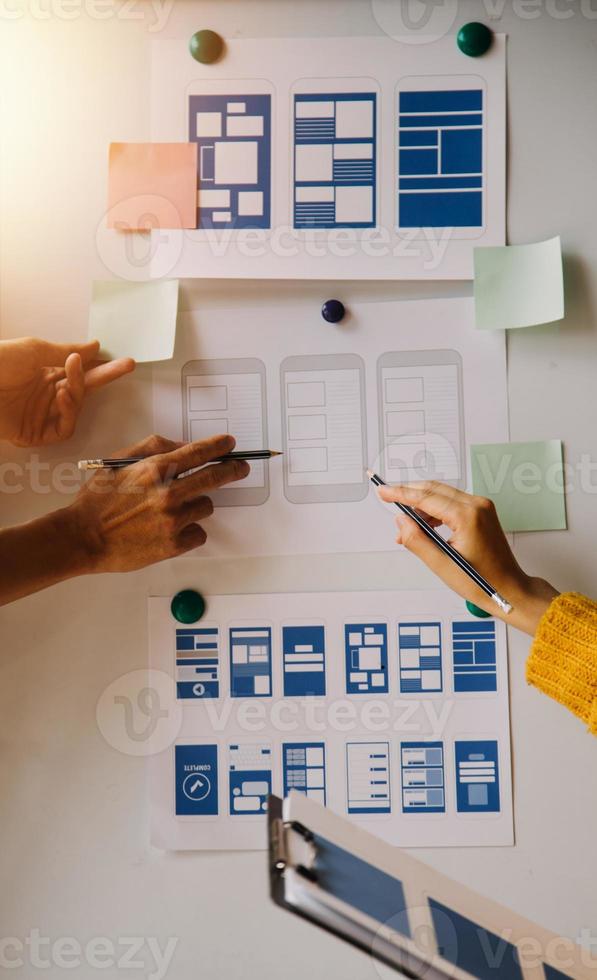 Close up ux developer and ui designer brainstorming about mobile app interface wireframe design on table with customer breif and color code at modern office.Creative digital development agency photo