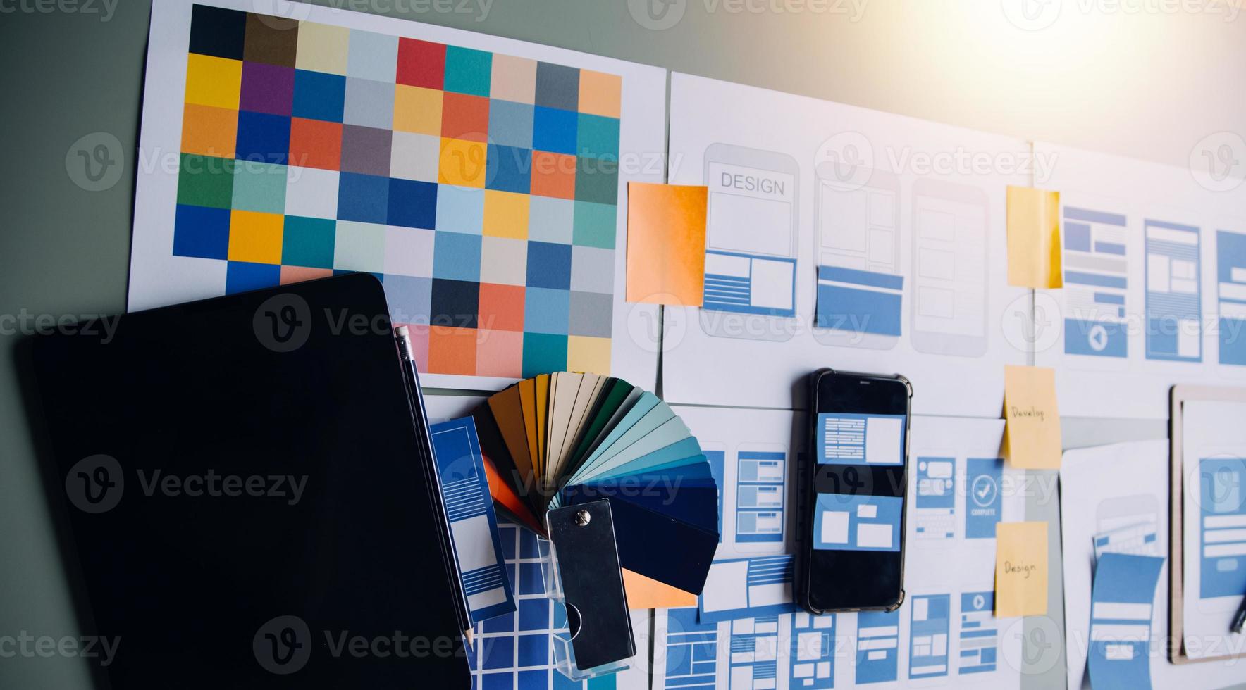 Close up ux developer and ui designer brainstorming about mobile app interface wireframe design on table with customer breif and color code at modern office.Creative digital development agency photo