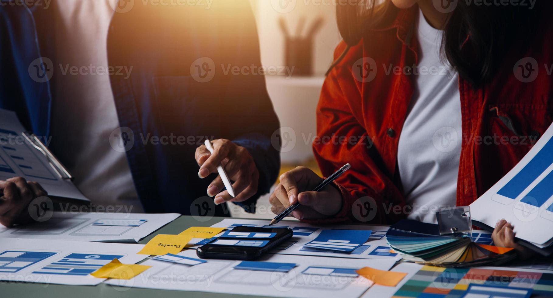 Close up ux developer and ui designer brainstorming about mobile app interface wireframe design on table with customer breif and color code at modern office.Creative digital development agency photo