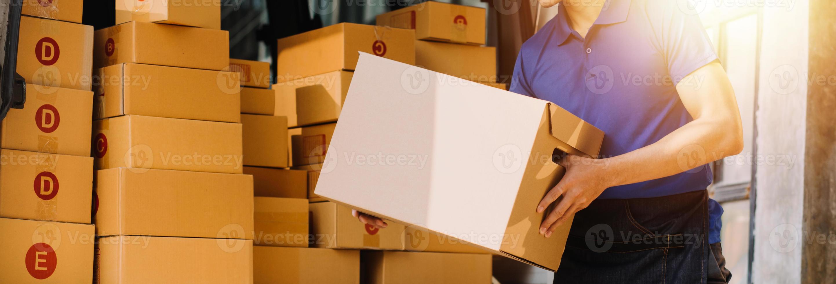 Startup small business entrepreneur of freelance Asian woman using a laptop with box Cheerful success Asian woman her hand lifts up online marketing packaging box and delivery SME idea concept photo