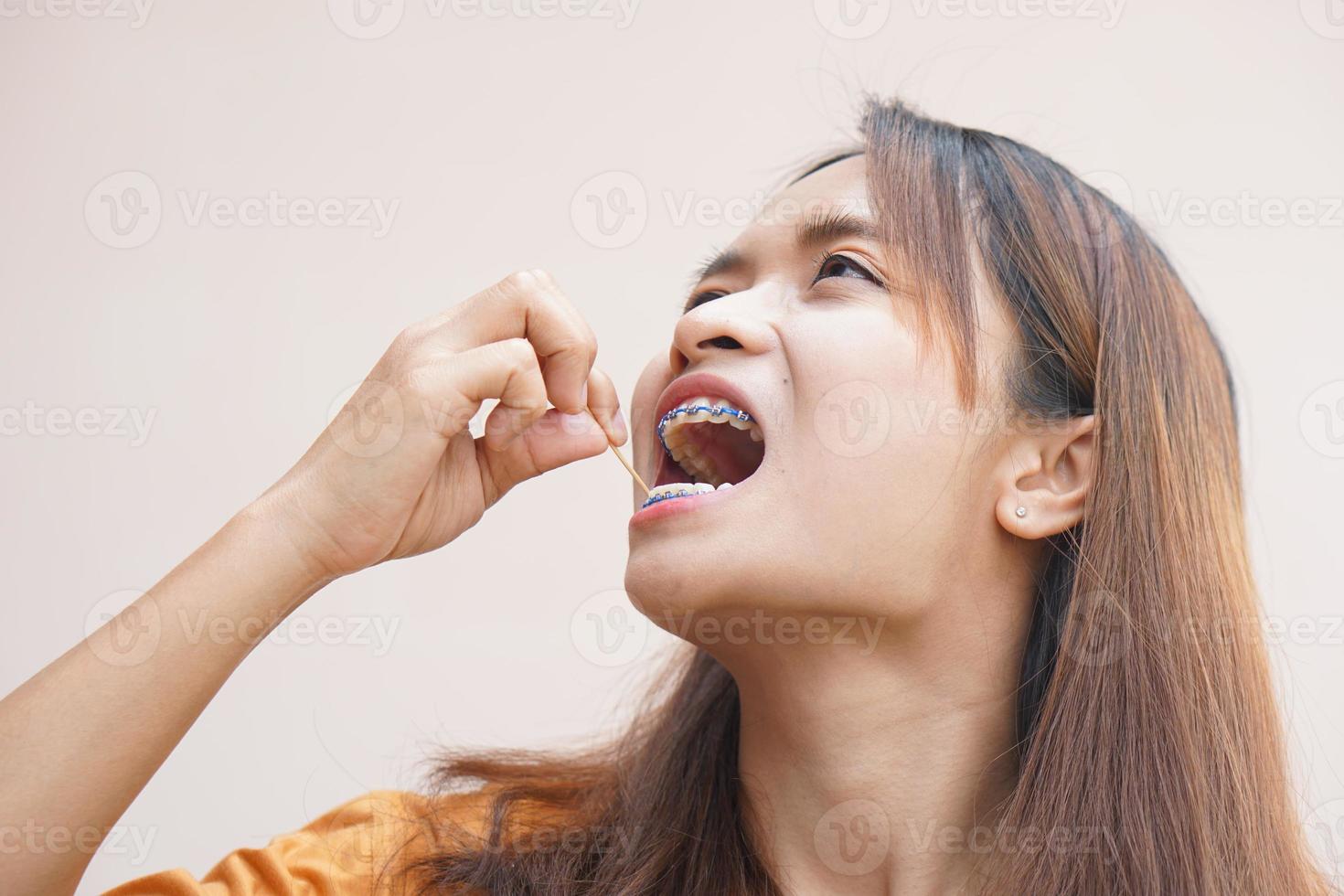 asiático mujer cosecha comida residuos desde su dientes foto