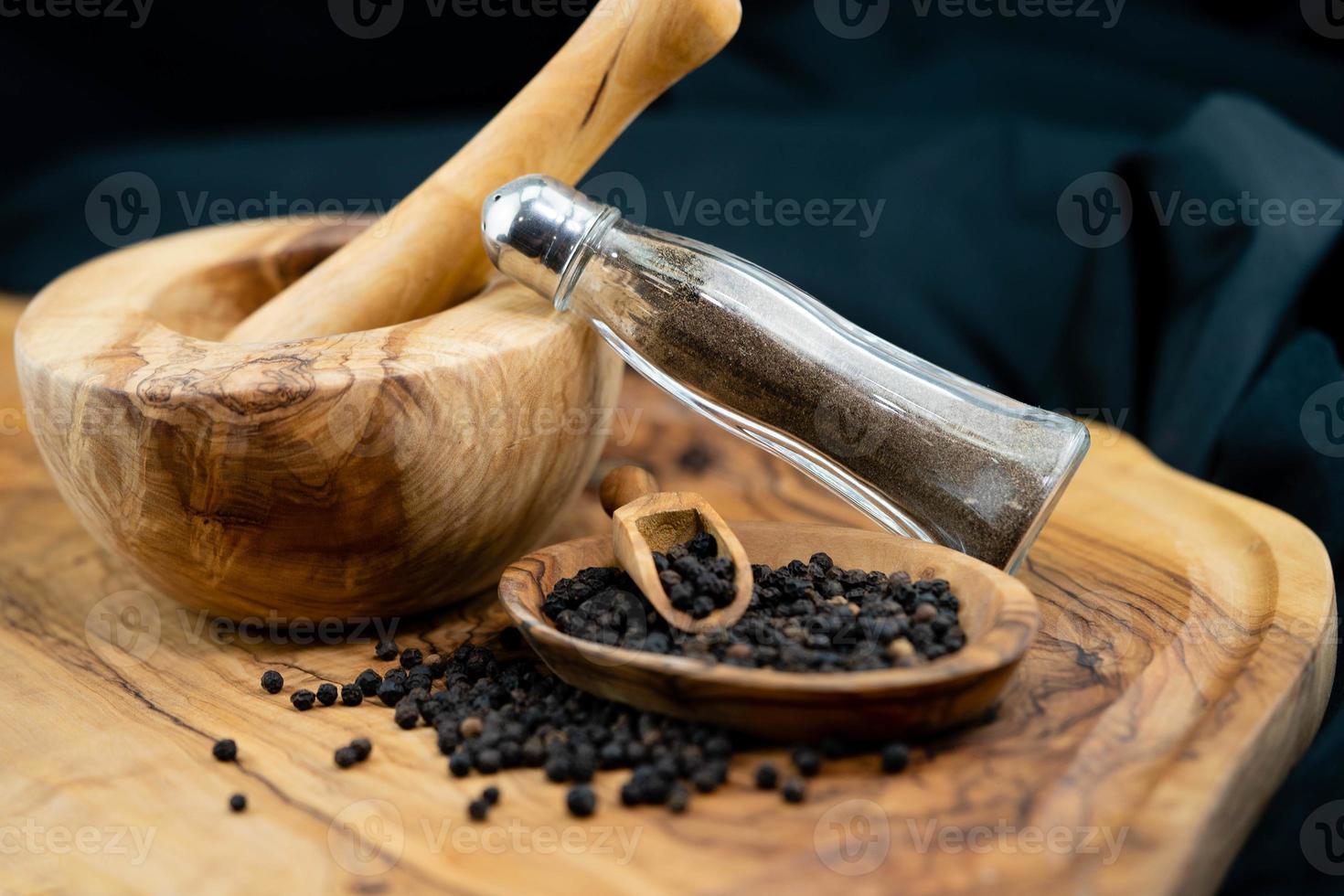 many black peppercorns on olive wood photo