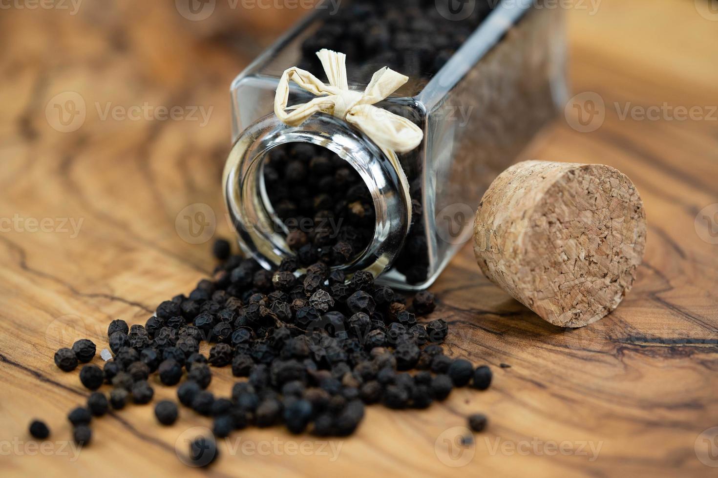 many black peppercorns on olive wood photo