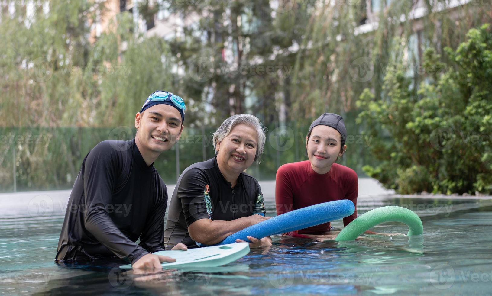 joven entrenador Ayudar mayor mujer en agua aeróbicos y trabajando fuera en el piscina. antiguo mujer y maduro hombre haciendo agua aeróbicos ejercicio en nadando piscina, mayor Deportes, y activo estilo de vida concepto. foto