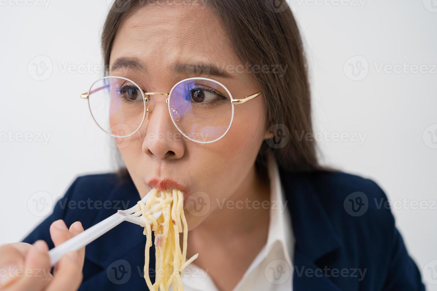 Busy and tired businesswoman eating spaghetti for lunch at the Desk office and working to deliver financial statements to a boss. Overworked and unhealthy for ready meals, burnout concept. photo