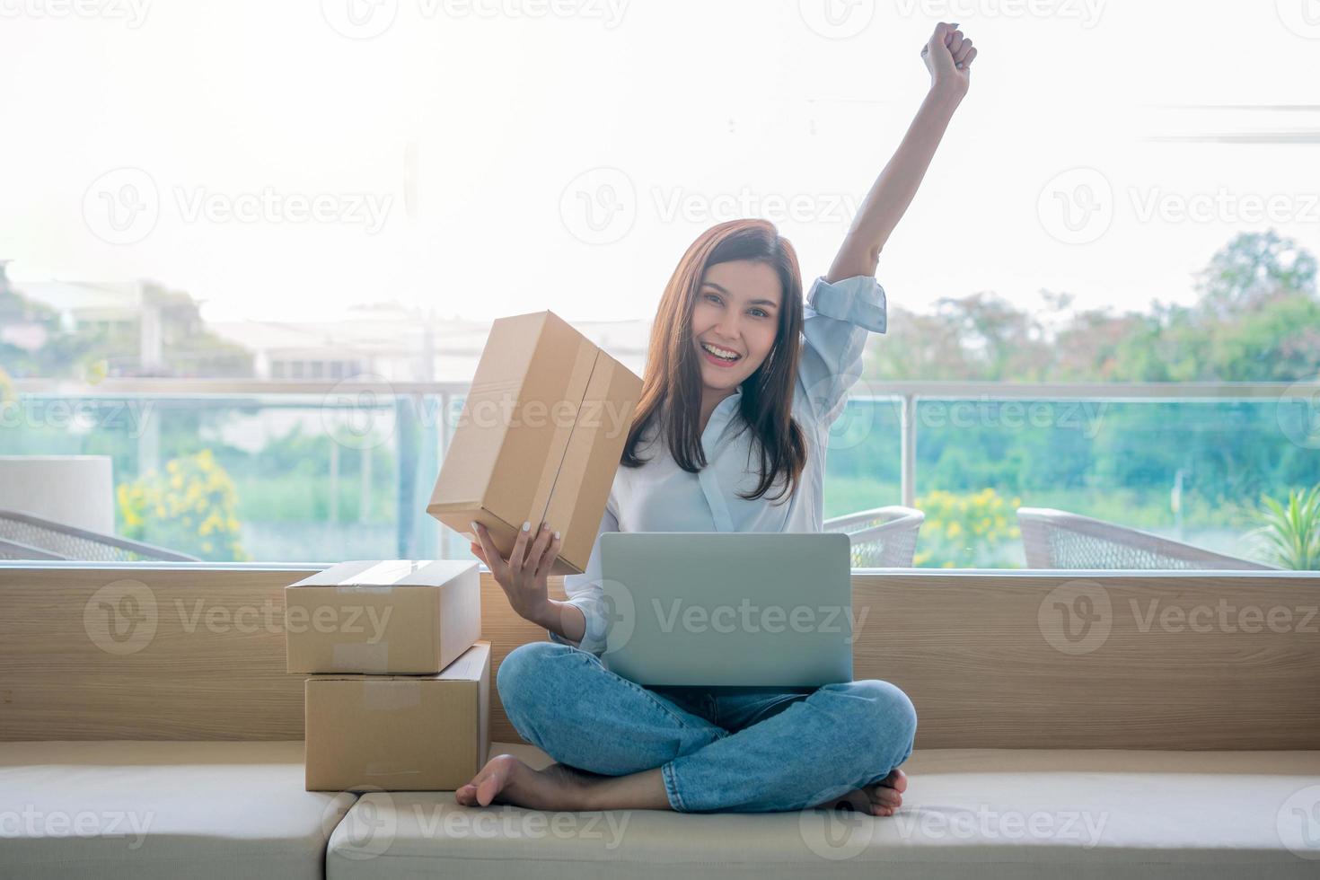 Happy young Asian woman entrepreneur, Smile for sales success after checking order from online shopping store in a laptop at home office, Concept of merchant business online and eCommerce photo