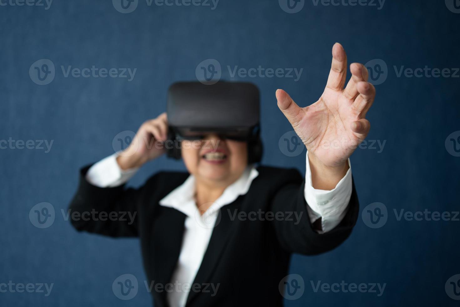 Senior Business woman wearing smart virtual glassest for Video conference, VR  headset glasses technology in modern offices and posing finger pointing and touching. Metaverse concept. photo