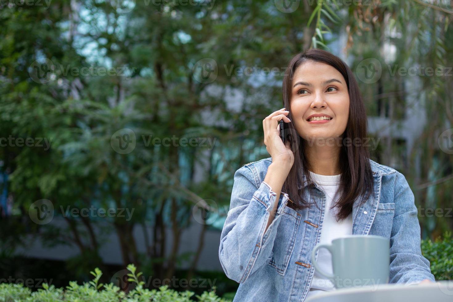 joven asiático mujer persona de libre dedicación participación teléfono inteligente para hablando con amigo. estilo de vida mujer trabajando a hogar concepto. sentado en matorral de tropical. niña en fiesta sentado en jardín sonriente relajante. foto