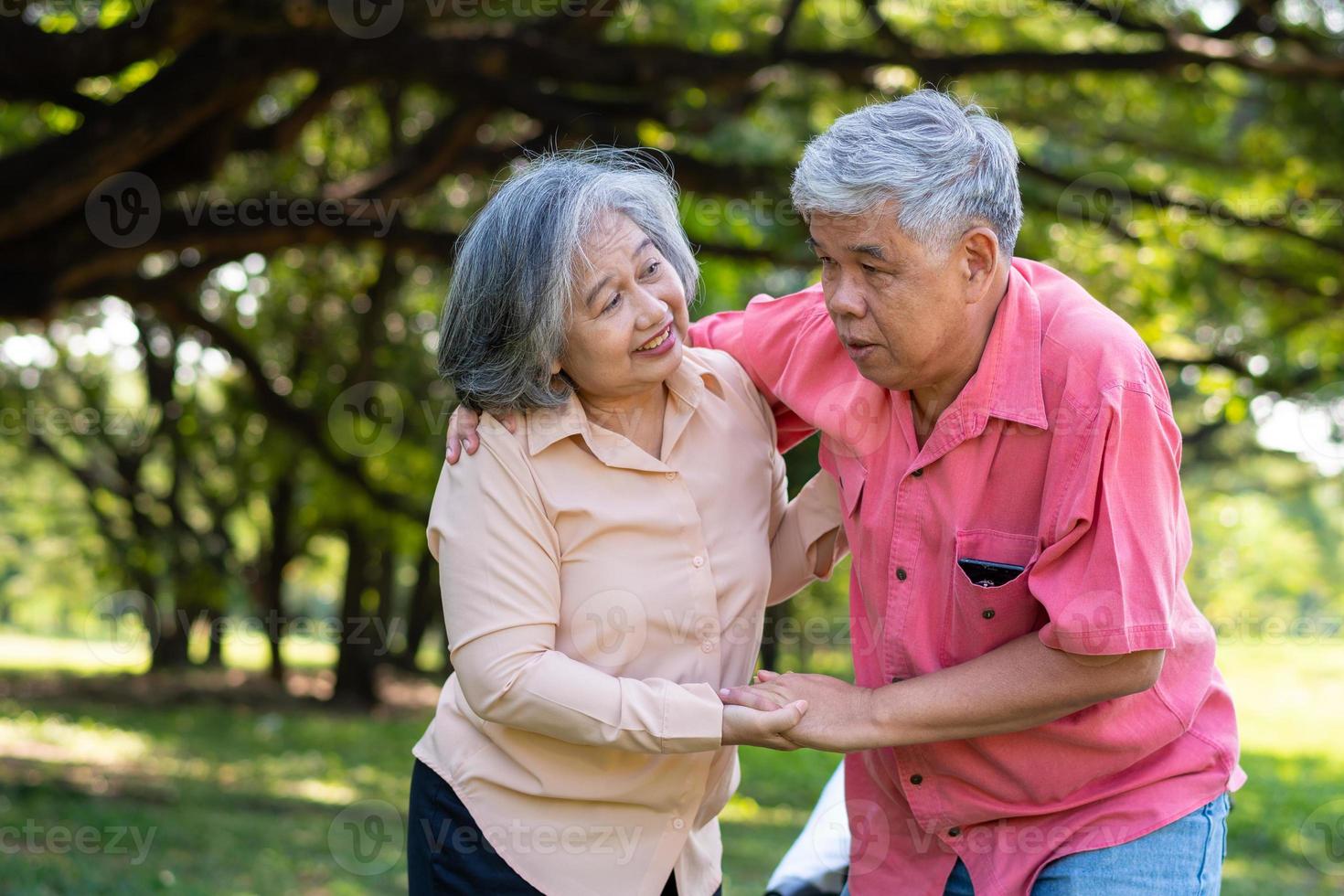 Asian senior man falling down on lying floor at park after Stumbled  and Crying in pain and him wife came to help support. Concept of old elderly insurance and health care photo