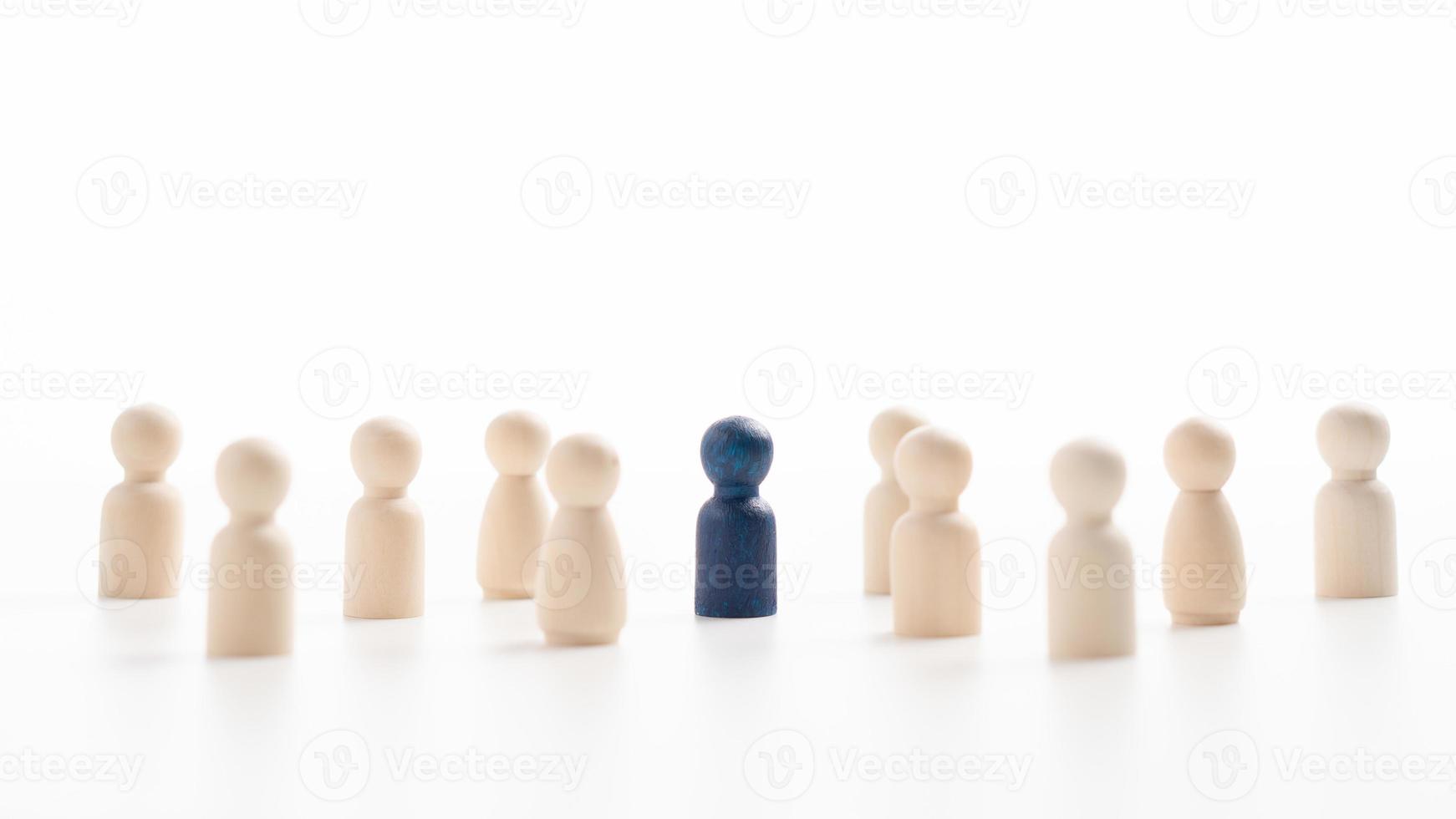 A wooden figure standing with a team to influence and empower. Concept of leadership, successful competition winner and Leader with influence and Social distancing for a new normal lifestyle photo