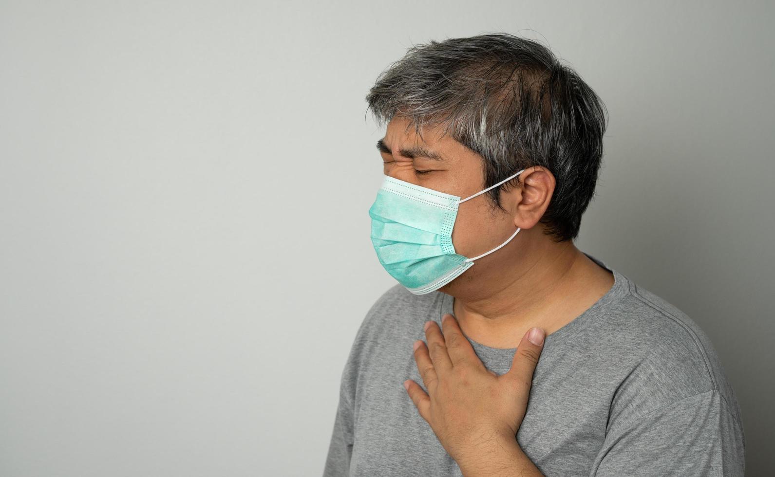 hombre asiático enfermo con una mascarilla médica y tosiendo y cubriendo su boca con mi mano. concepto de protección coronavirus pandémico y enfermedad respiratoria foto