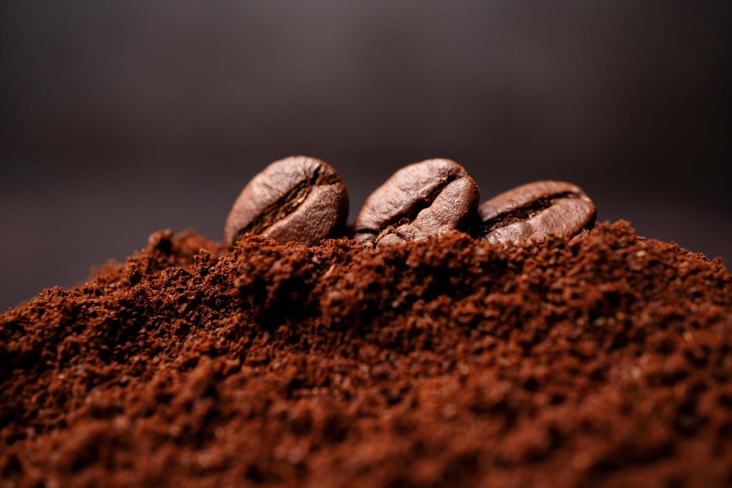 Closeup of three coffee beans at the mixed heap of roasted coffee with copy space for text. Concept of Coffee freshness photo