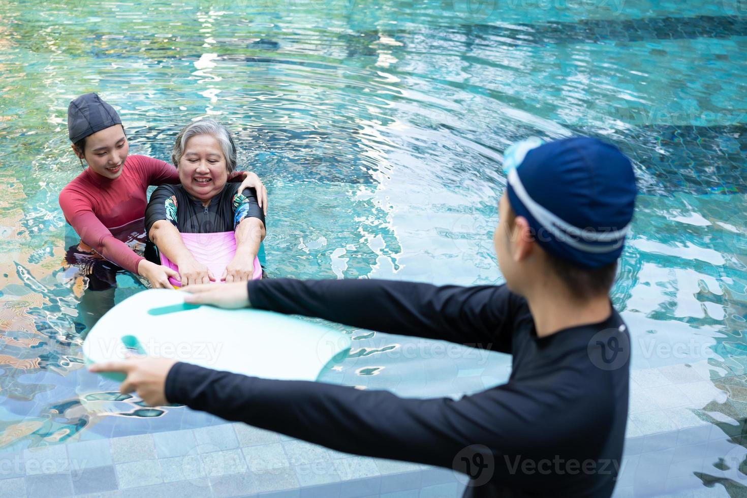 joven entrenador Ayudar mayor mujer en agua aeróbicos y trabajando fuera en el piscina. antiguo mujer y maduro hombre haciendo agua aeróbicos ejercicio en nadando piscina, mayor Deportes, y activo estilo de vida concepto. foto