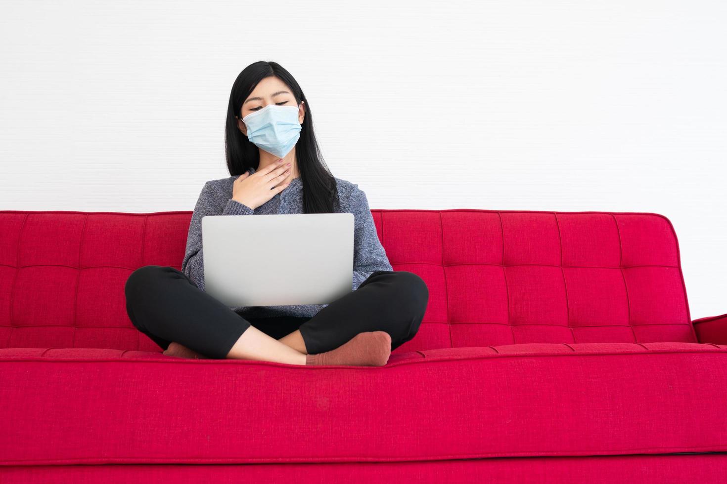 mujer cansada con mascarilla, frío y dolor de cabeza, el sufrimiento del síndrome de la oficina después de largas horas de trabajo en la computadora. Síndrome de oficina y concepto de atención médica. foto